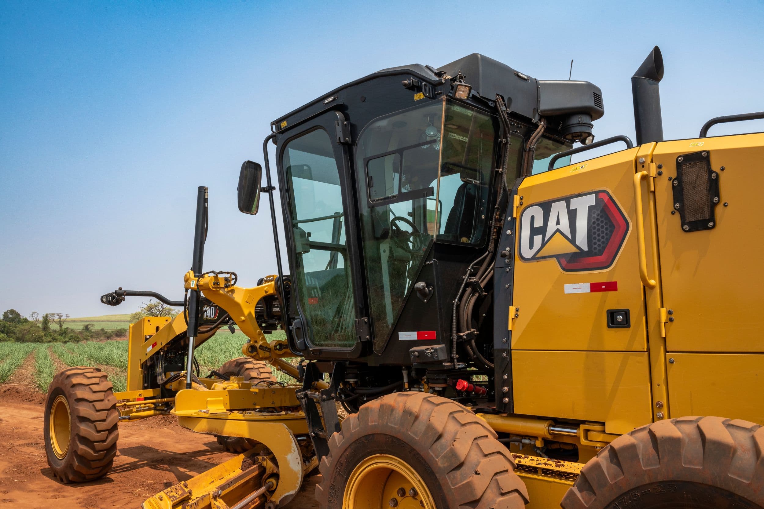 140 Motor Grader grading dark red dirt. This machine has a lever and steering wheel control system.