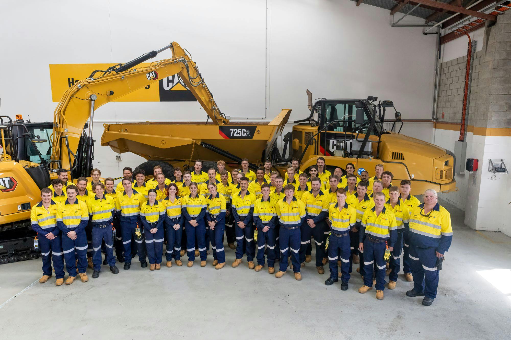 People & Careers: 2024 Apprentices in front of 725C Articulated Truck and Excavator